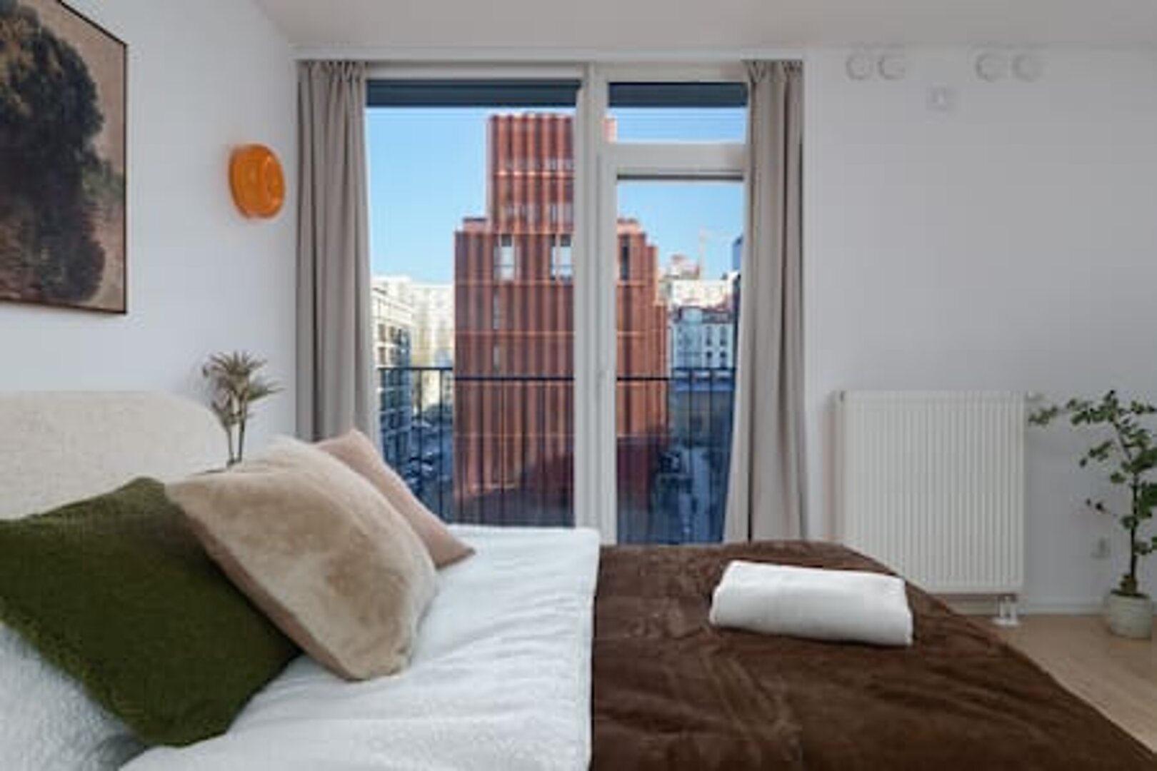Sypialnia apartamentu THE WAW w Browarach Warszawskich z widokiem na ceglane budynki osiedla